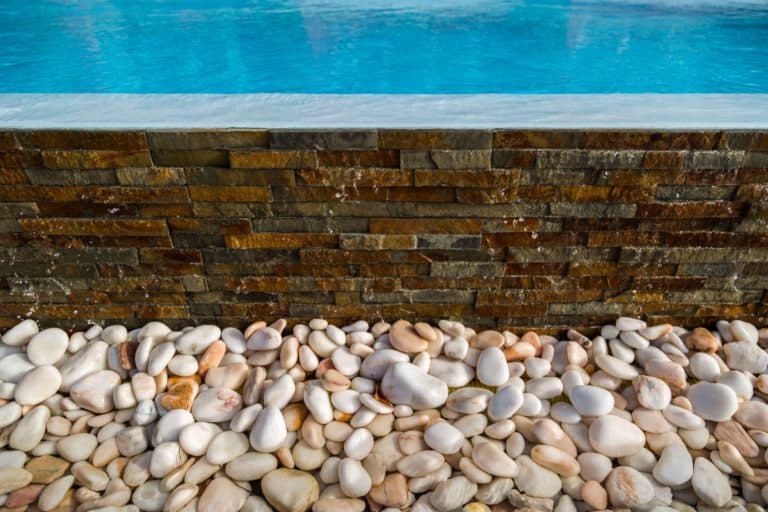 Pormenor de piscina com água cristalina e bordadura em pedra